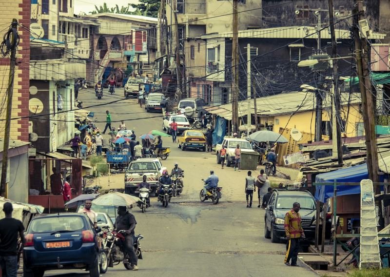 A busy city street with cars, motorcycles and pedestrians