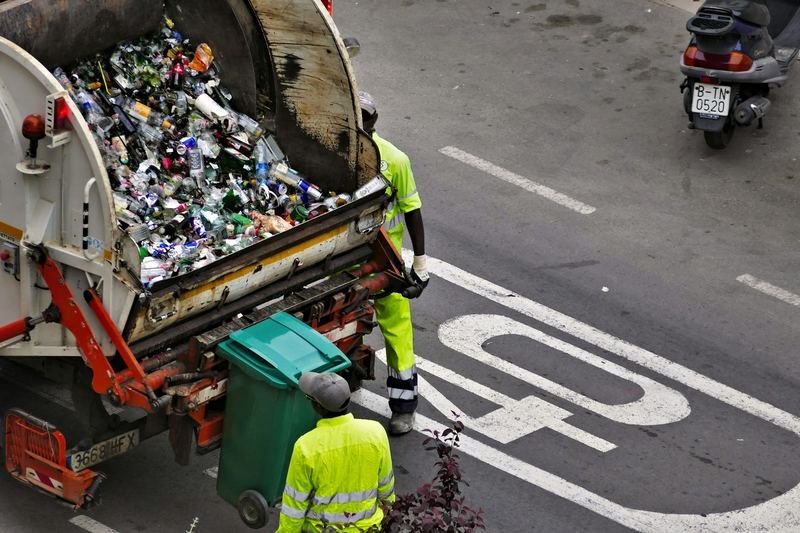 Workers in high-visibility clothing emptying a bin into a waste collection truck
